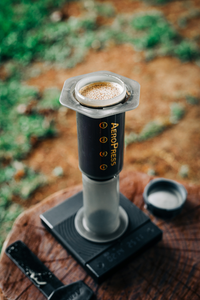 an Aeropress coffee maker being used on a camp trip